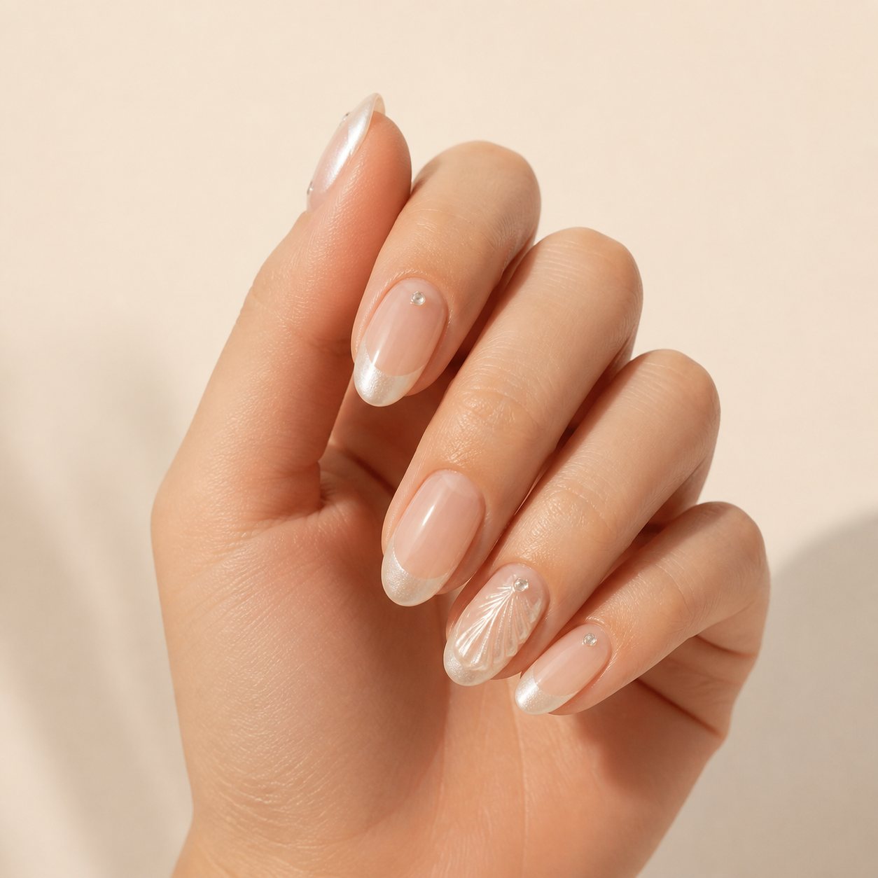 Hand wearing pearl French press-on nails with crystal accents